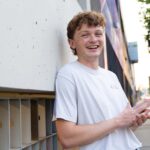 Photo of Will Linley smiling and leaning against wall